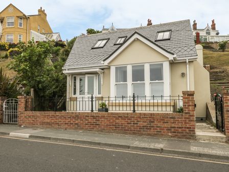A small house with a tiled roof and three skylights fronted by a brick wall and metal fence at Sunrise in Filey