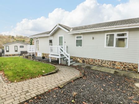 A single-story house with steps leading to the door a lawn and a paved walkway at The Lookout in Stepaside