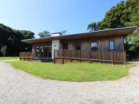 A single story wooden house with large windows and a gravel driveway at Elm in Truro
