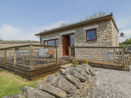 A stone house with a wooden deck and outdoor furniture surrounded by a stone wall at Boavista in Carnforth