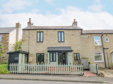 A stone house with a picket fence and a small porch at Skovhaven in Catton