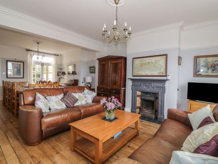A living room with leather sofas a wooden coffee table a fireplace and a dining area at Lighthouse View in Gorleston-on-Sea