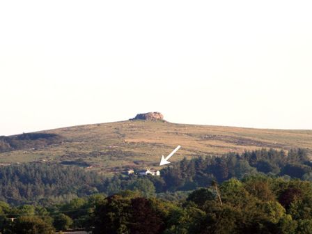 A hillside with a small house among trees and a rocky outcrop on the hilltop at Kestorway in Chagford