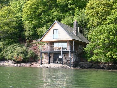 A boathouse on stilts by the water surrounded by trees at Sandridge Boathouse in Stoke Gabriel