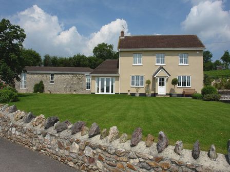 A two-story house with a stone extension and a green lawn with a stone wall in front at Lower Wadden Farmhouse and Annexe Southleigh near Beer