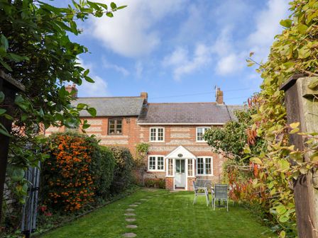 A garden with a house in the background at Poppy Cottage Charlton Marshall
