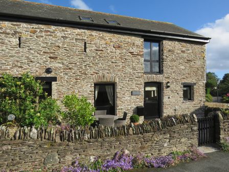 A stone cottage with a small garden and outdoor seating area at Bramble Cottage in Ringmore
