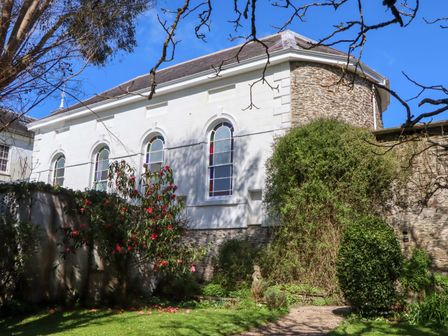 A garden with a building and plants at The Music Room near Aveton Gifford