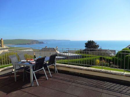 An outdoor patio with a table and chairs overlooking the sea at 3 Tarifa in Bigbury-on-Sea