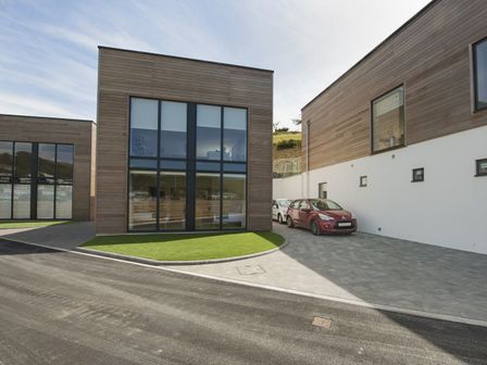 A modern building with large windows and parked cars on a driveway at 5 Beachdown in Challaborough near Bigbury on sea