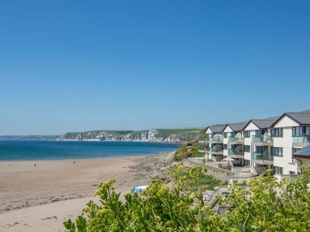A coastline with sandy beach and modern houses by the shore at 13 Burgh Island Causeway in Bigbury-on-Sea