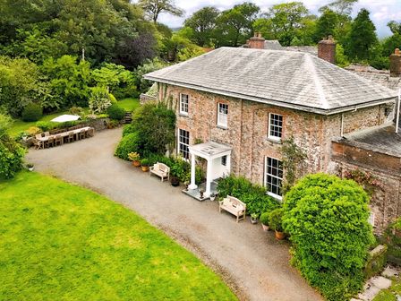 An outdoor view of a house with a garden and seating area at Parnacott in Holsworthy