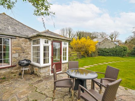 An outdoor seating area with a table and chairs at Tumrose Cottage in Blisland