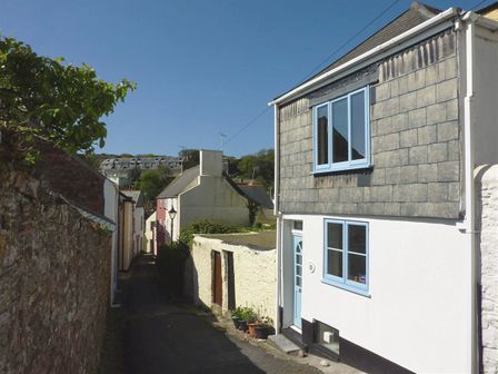 A narrow street with houses on both sides and potted plants near the door at Chough Cottage in Kingsand And Cawsand