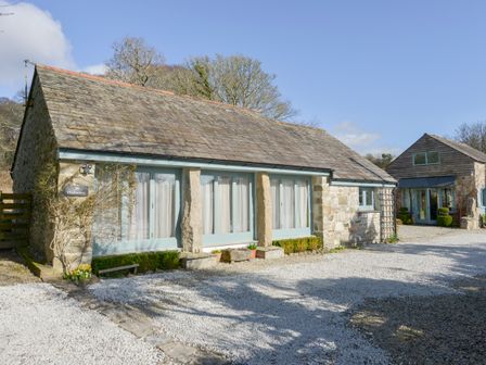A stone cottage with blue-framed windows and a gravel driveway at Hideaway Barn in Charlestown