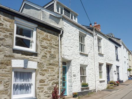 A street view of stone and white painted cottages with windows and doors and flower pots at Quarry Cottage in Flushing near Falmouth