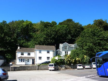 A parking lot in front of two houses with trees in the background at Stones Throw in St Mawes