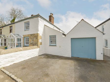 A white stone cottage with blue window frames and a blue garage door at 2 Trerise Cottage in Manaccan