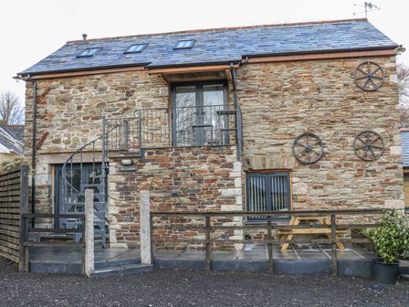 Stone house with slate roof spiral staircase and wooden picnic table on patio at The Cart House in Dobwalls