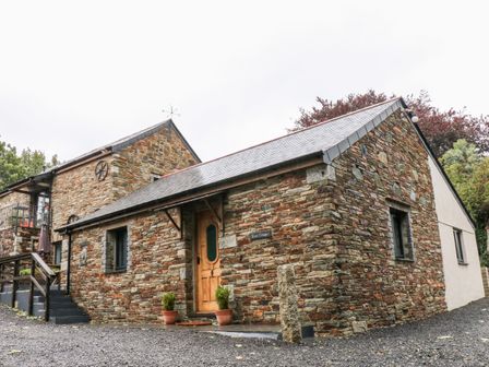 Stone cottage with wooden door and small plants outside at Elvan Cottage in Liskeard