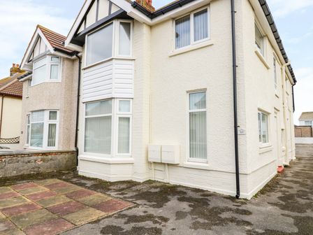 The exterior of a two story semi detached house with bay windows and a tiled driveway at Beside The Sea - Ar Lan y Mor in Llandudno