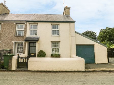 A two-story house with a front garden and a garage with a blue door at Glascoed in Edern