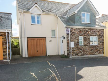A house with a garage door driveway and stone wall section at Jacks Mews in Tintagel