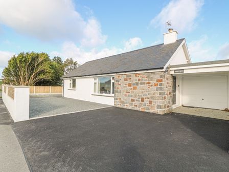 A single story house with a stone and white exterior and a garage at Trem Y Garn in Morfa Nefyn