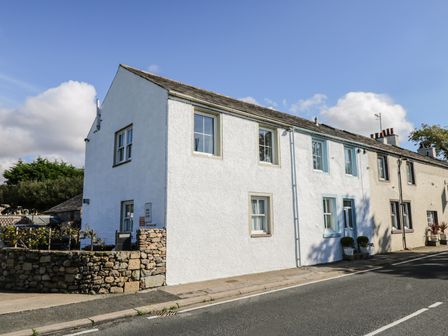 A row of terraced houses along a street with stone walls and potted plants at 1 Park Nook Close in Waberthwaite