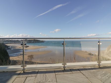 A glass balcony overlooking a sandy beach and ocean at Buena Vista in Newquay