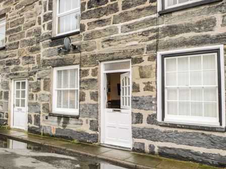 The stone exterior of a building with white framed windows and doors at Llys Madoc in Porthmadog