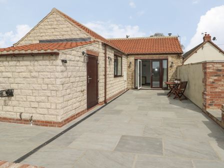 An outdoor patio area with stone tiles and a table with two chairs near a building at Laurel Farm in Scagglethorpe near Rillington