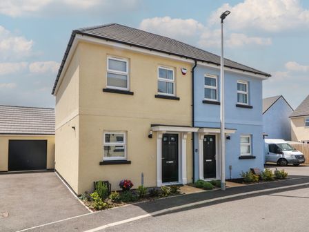 A two-unit semi detached house with yellow and blue walls two black doors and a street lamp at Harleys Hideaway in Appledore