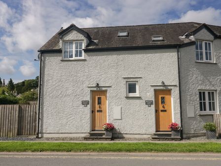 A white two story house with two wooden doors and flower pots at Bettys Mews in Hawkshead