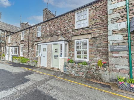 A row of stone cottages with small front gardens and multiple white windows at Poppy's Cottage in Grasmere