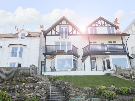 A row of white houses with black timber framing and balconies with outdoor chairs at Flat 3 Peacehaven in Sandsend near Whitby