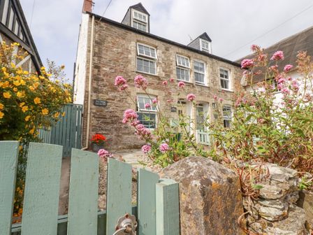 Stone cottage with green gate and pink flowers in front at Dale Cottage in Crantock