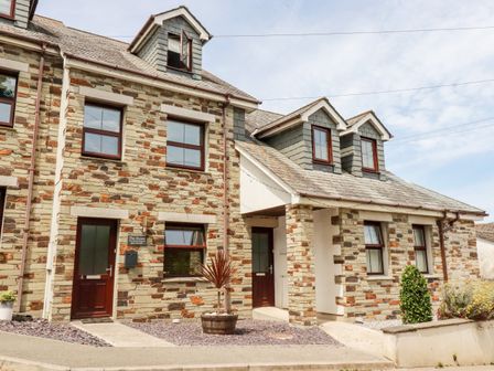 The exterior of a two story stone house with multiple windows and doors at The Dunes in Crantock