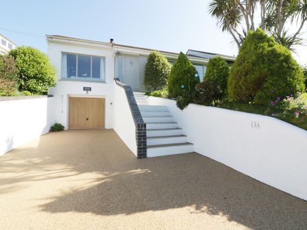 A front view of a house with a garage door driveway stairs and garden Keelyn Crantock