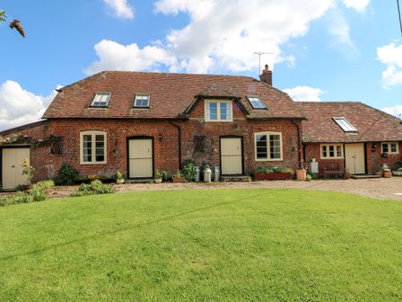 A brick house with cream doors and windows and a green lawn in front at Downs View Dairy in West Tytherley