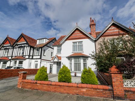 A row of houses with red brick walls and green bushes in front at Westpoint in Llandudno