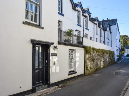 A street view of white terraced houses with black framed doors and windows at Serendipity in Fowey
