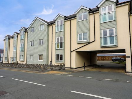 Exterior view of a residential building with multiple windows and a driveway at Tides Reach in Rhosneigr