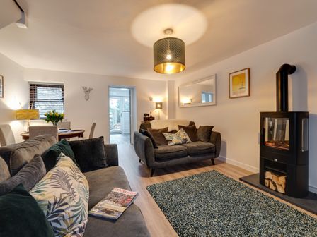 A living room with two sofas a wood burning stove a dining table with chairs and a rug at 2 Ysgoldy Bethesda Bangor