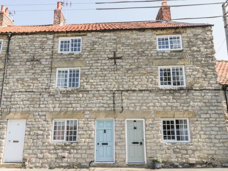 Stone cottage facade with three doors and multiple windows on the front at Crooked Cottage in Kirkbymoorside