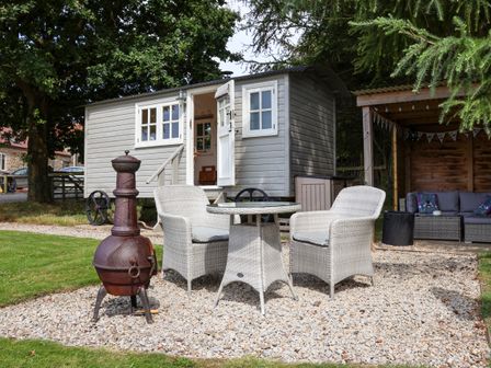 An outdoor seating area with a table and two chairs next to a small shed and a covered seating area at Bellwether in Helmsley