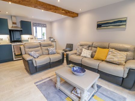A living room with two sofas a coffee table with bowls and an open kitchen at 7evern  Porth Farm in Caersws