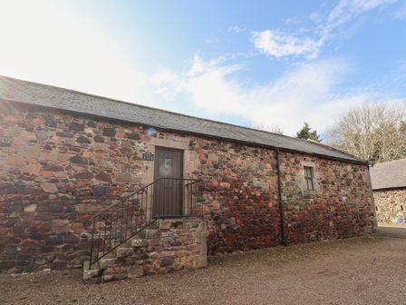 A stone building with a small staircase leading to a door and a window at Foxglove Covet in Akeld near Wooler