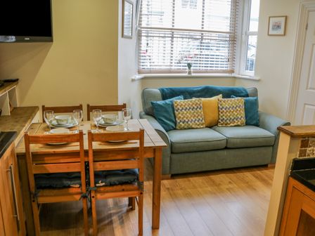 A dining table set with plates and glasses next to a sofa with cushions in a room at Apartment 6 in Whitby