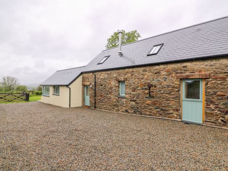 An exterior view of a stone and plaster building with a gravel driveway and light blue doors at Bwthyn Eisteddfa Fach in Brynberian near Newport